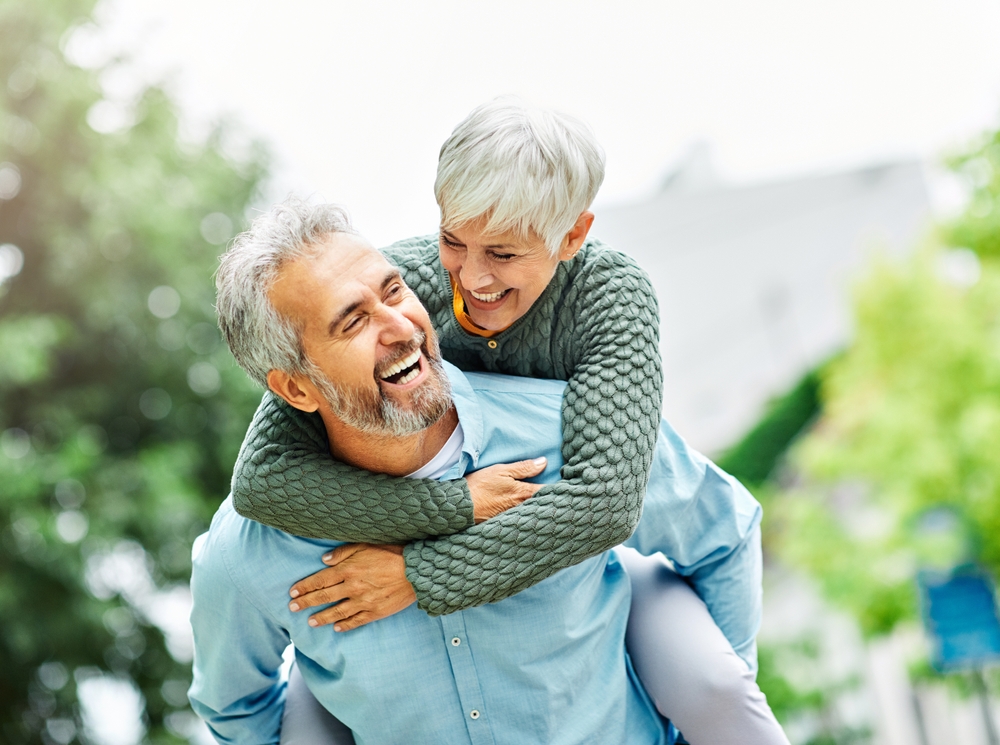 A joyful elderly couple, with the woman on the man's back, represents urgent care from emergency dentistry in Castle Rock at Castle Rock Family Dental